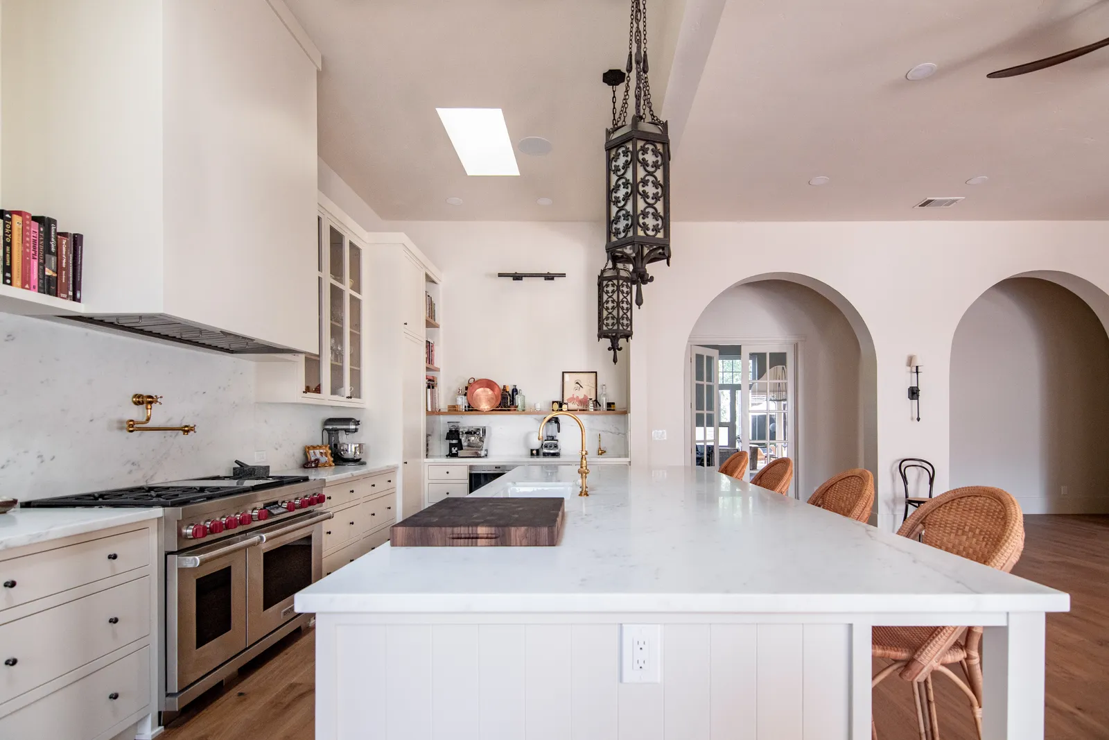 Kitchen with white marble island, iron lantern pendant, and arched openings connecting to the dining room